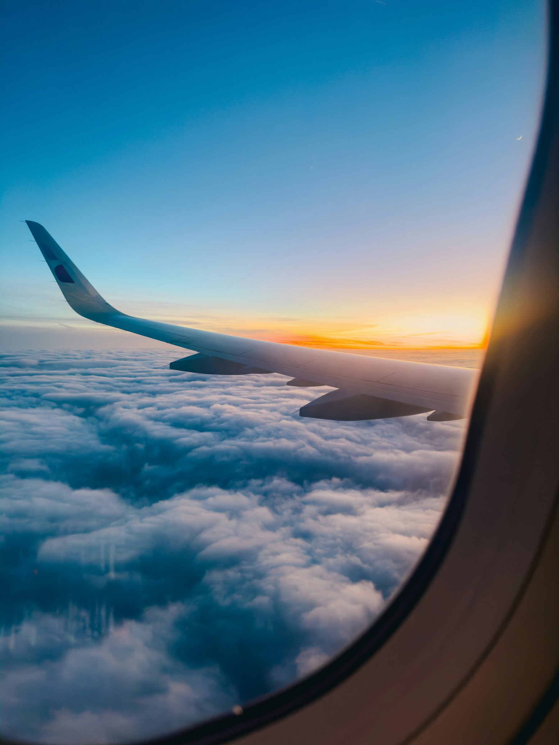 Aircraft wing above clouds at sunset